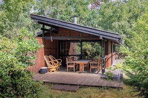 A wooden deck with outdoor furniture, a covered seating area, and a chimney.