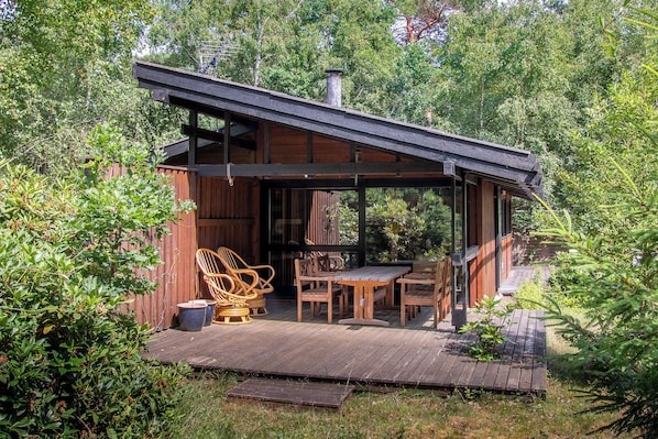 A wooden deck with outdoor furniture, a covered seating area, and a chimney.