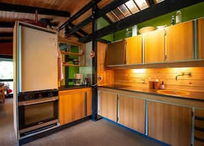 A compact kitchen with wooden cabinets, a built-in oven, and a sink.