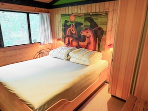 A wooden-framed bedroom with a bed, a window with curtains, and a wall painting. - Architect‑designed 1976 summer house near beach (Store Fuglede)