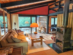 A cozy living room with a sofa, a table, and a fireplace. - Architect‑designed 1976 summer house near beach (Store Fuglede)