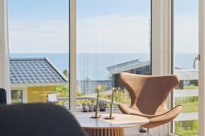 Una habitación con vista al mar, una silla y una mesa con velas.