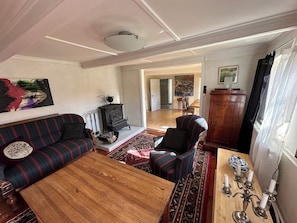 Ein Wohnzimmer mit Sofa, Sessel, Couchtisch aus Holz und einem gemusterten Teppich.
