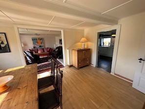 A spacious living room with a wooden dining table, a sofa, and a cabinet.