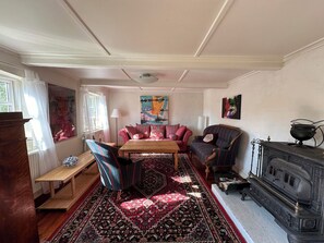 Ein traditionell eingerichteter Raum mit Sofa, Ohrensessel, Holztisch und Kamin.