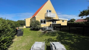 A yellow house with a red roof, a balcony, and a wooden deck with lounge chairs. - Holiday Flat in Skagen town (Skagen)