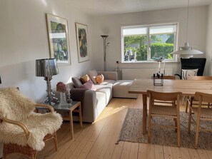 A living room with a sofa, a dining table, a lamp, and a chair.