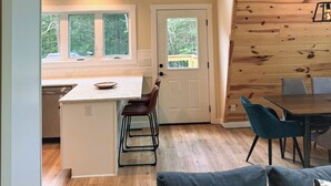 A spacious loft with a high ceiling, wooden beams, a kitchen with a central island, and a dining area with modern chairs.