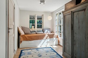 Une chambre à coucher avec un lit, une fenêtre, une porte et une armoire.