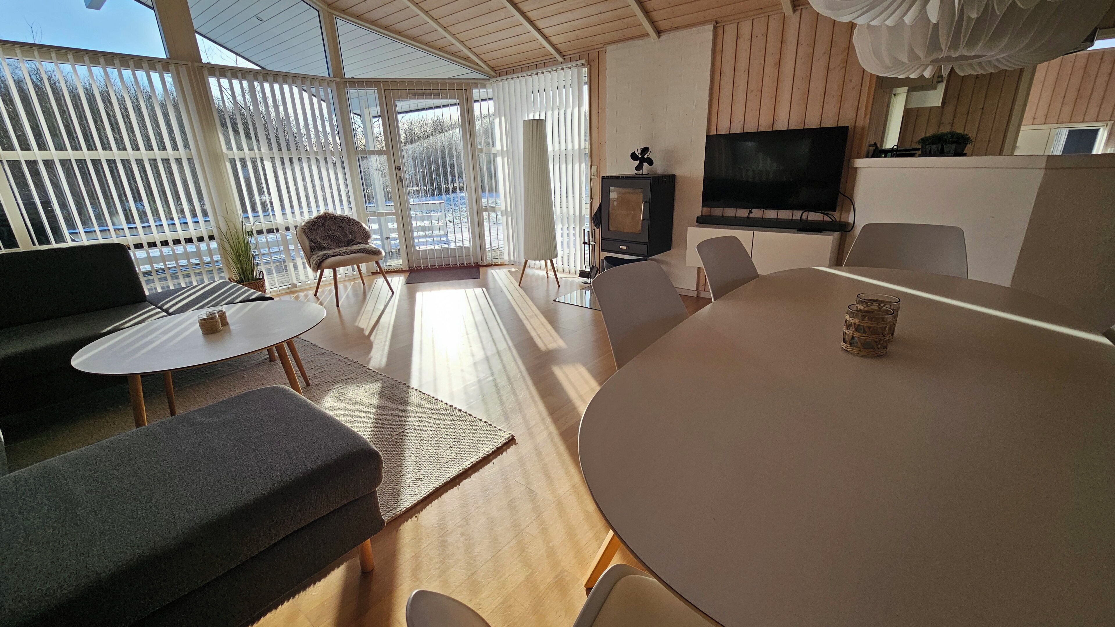 Moderni olohuone, jossa on sohva, pyöreä pöytä ja televisio.