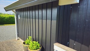 Un bĂątiment Ă lâextĂ©rieur sombre, avec le chiffre « 16 » peint sur le mur et deux plantes en pot posĂ©es sur le sol.