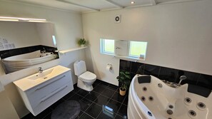 Une salle de bain moderne Ă©quipĂ©e dâune baignoire, de toilettes, dâun lavabo et dâun miroir.