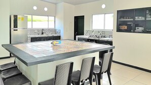 A modern kitchen with a central island, black chairs, and a refrigerator. - Excepcional CASA FINCA piscina wi-fi tv (Tocaima)