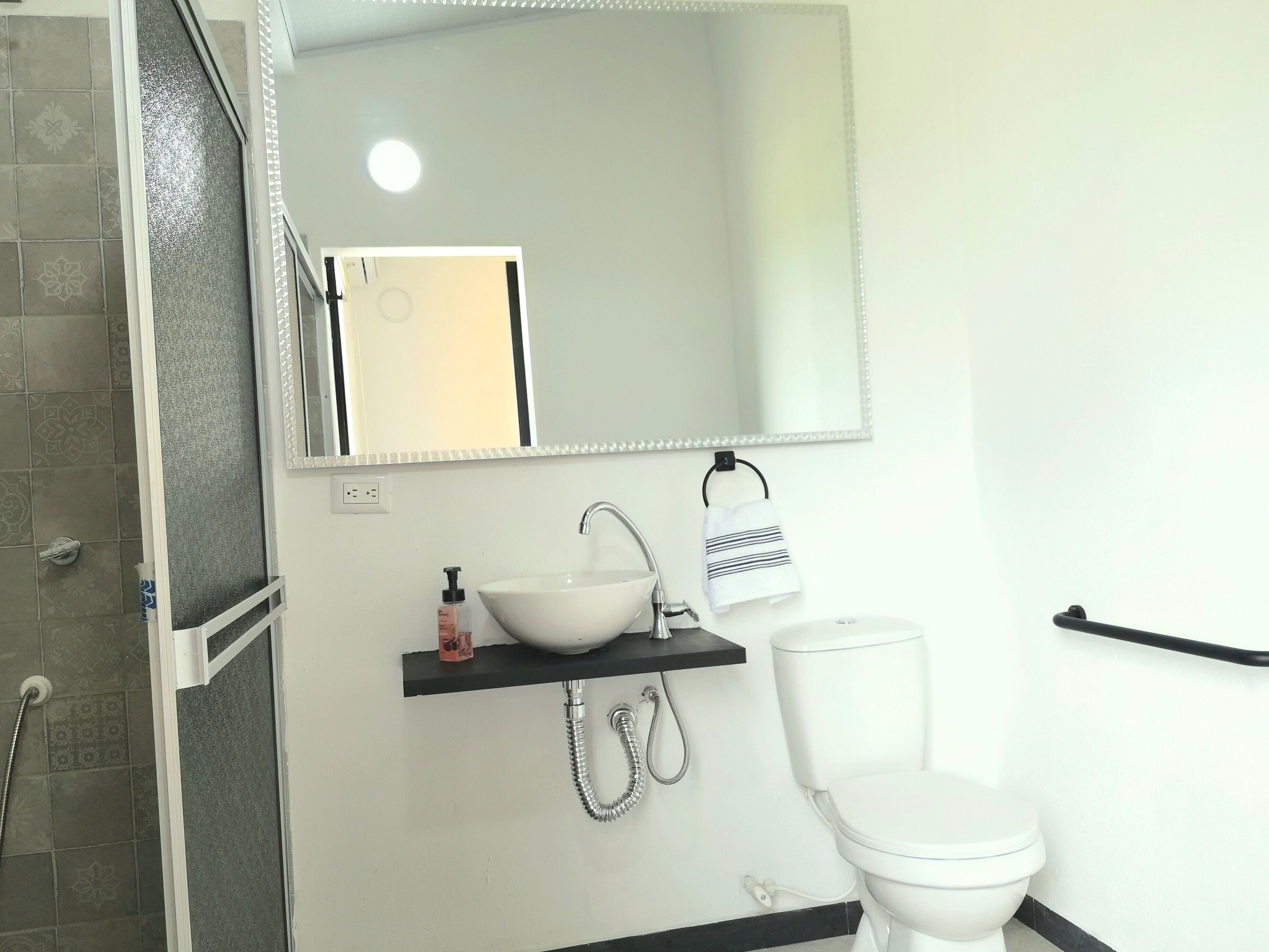 A bathroom with a white sink, a mirror, a towel rack, and a toilet.