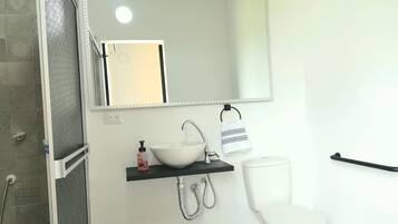 A bathroom with a white sink, a mirror, a towel rack, and a toilet.