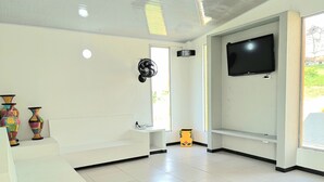A room with a white tiled floor, a flat-screen TV mounted on the wall, and two colorful vases on a shelf. - Excepcional CASA FINCA piscina wi-fi tv (Tocaima)