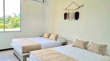 A hotel room with two beds, a large window, an air conditioning unit, and a wall-mounted decorative item.