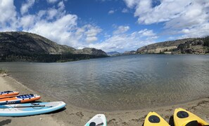 A lake with kayaks and a paddleboard on the shore. - Beach Front, Lake, Fishing, Canoe, Paddle boards #4 (Oliver)