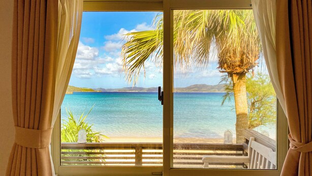 A room with a view of a beach and ocean through a sliding door. - Le Grand Bleu (Tatsugo)