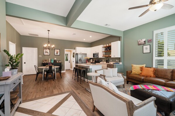 A spacious living area with a dining table, sofas, and a kitchen in the background.