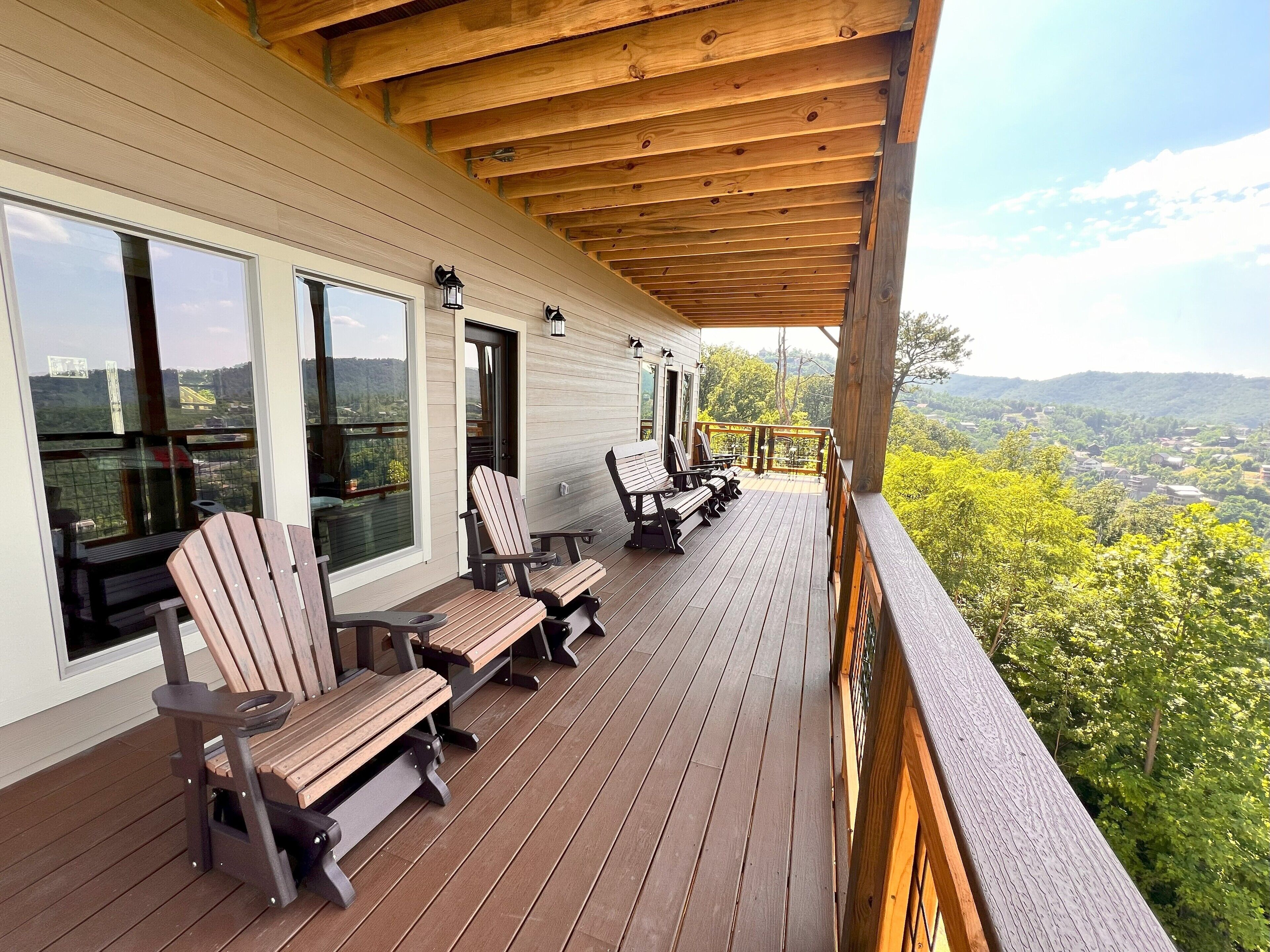 A wooden deck with outdoor seating and large windows overlooking a scenic landscape.