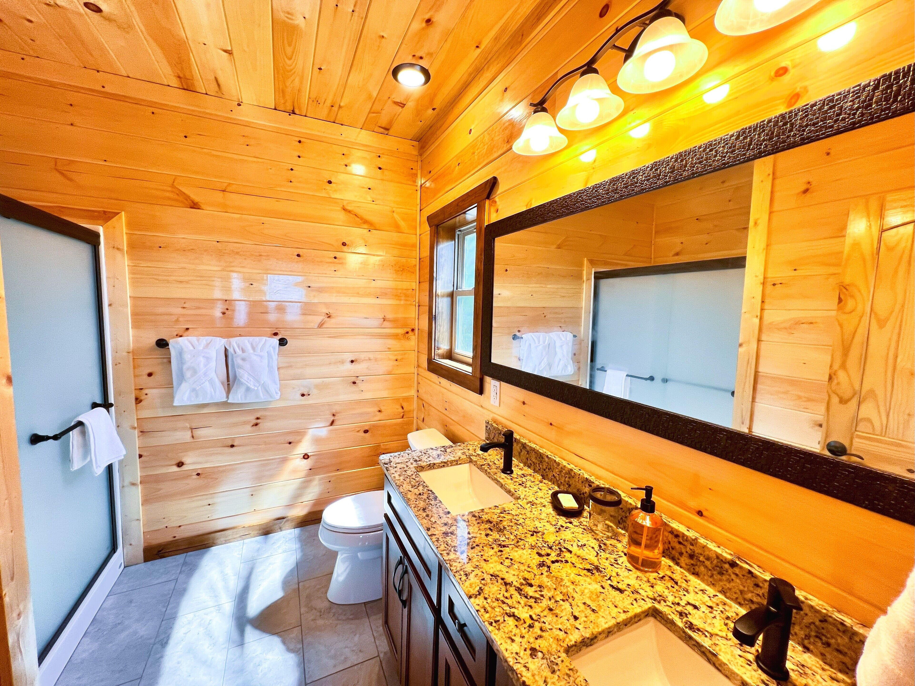 A wooden-paneled bathroom with a sink, mirror, and toilet.