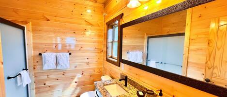 A wooden-paneled bathroom with a sink, mirror, and toilet.