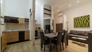 A modern kitchen with a dining area, a sofa, and a painting on the wall. - GuestHost - Trastevere Three Luxury Rooms (Roma)