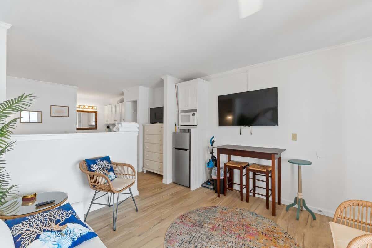 A compact living space with a dining area, kitchenette, and a flat-screen TV mounted on the wall.
