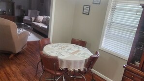 A dining area with a round table, chairs, and a ceiling fan. - Charming 3-bedroom house with 65in smart tv, Wifi, and central heat/air in town! (Melbourne)