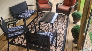 A covered outdoor patio with wicker furniture, a glass-top table, and a potted plant. - Charming 3-bedroom house with 65in smart tv, Wifi, and central heat/air in town! (Melbourne)