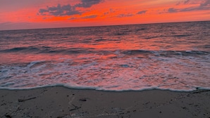 Ein Strand mit Wellen und einem Sonnenuntergang.