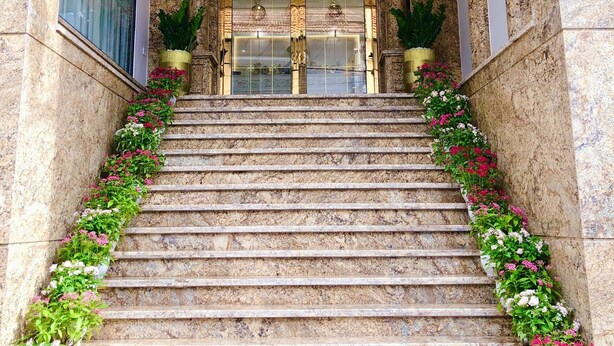 A grand entrance with marble steps, a chandelier, and potted plants. - Senior Hotel (Can Tho)