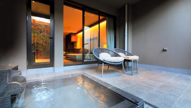 A modern hotel room with a glass door leading to a balcony, a hot tub, and two wicker chairs. - BLISSTIA Hakone Sengokuhara (Hakone)
