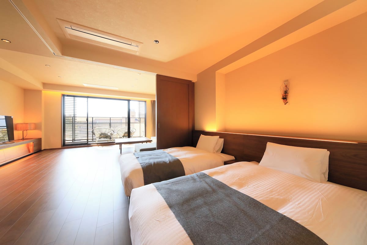 Una habitación de hotel con dos camas, un ventanal grande y vistas al exterior.