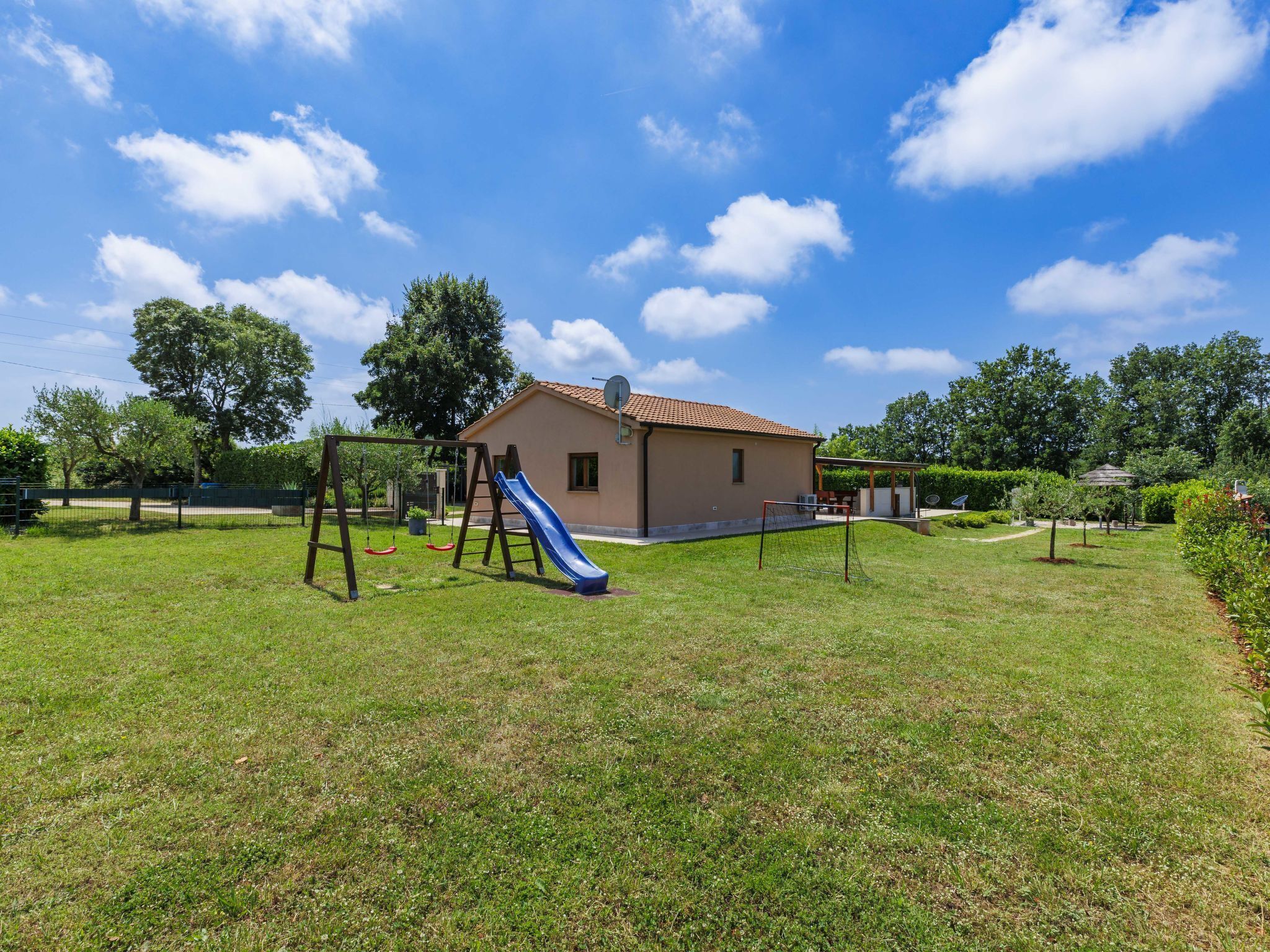 A house with a backyard containing a swing set and a slide.