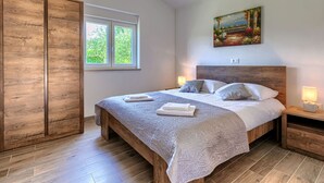 A bedroom with a large bed, a window, a painting, and wooden flooring. - Villa Paliska by Interhome (Poreč)