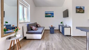 A modern living room with a sofa, a small table with a vase of flowers, a large mirror, and a painting on the wall. - Villa Paliska by Interhome (Poreč)