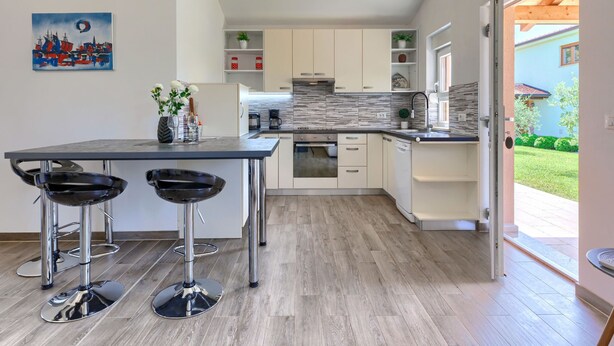 A modern kitchen with a central island, bar stools, and a view of the outside. - Villa Paliska by Interhome (Poreč)