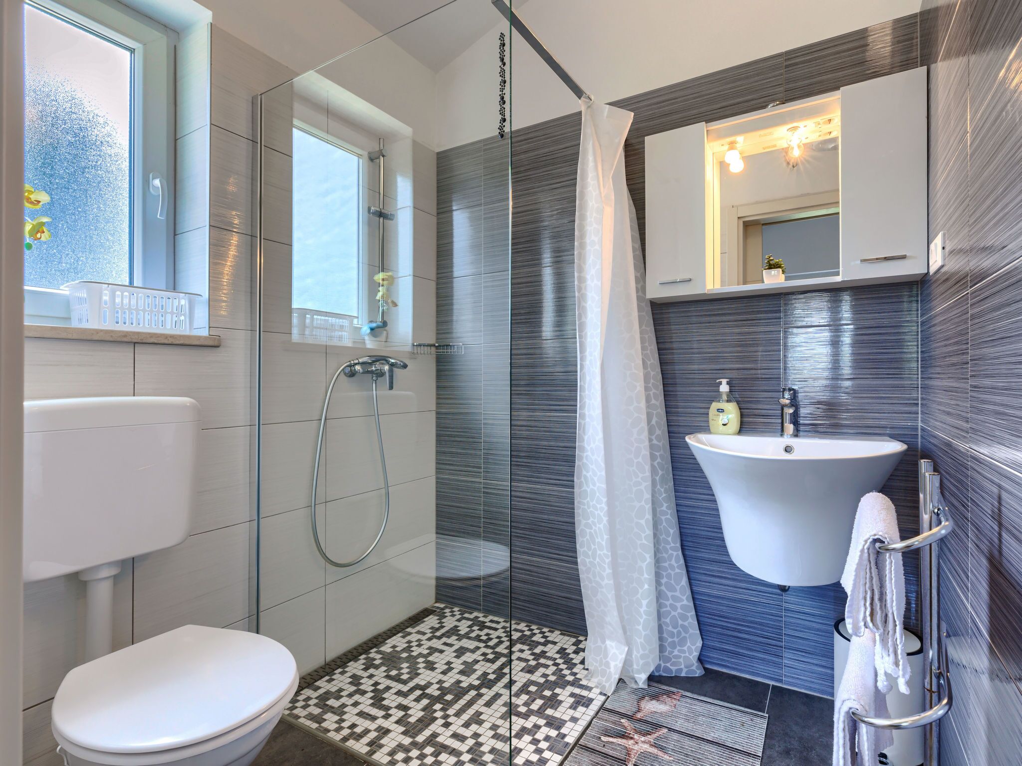 A modern bathroom with a shower, toilet, and sink.