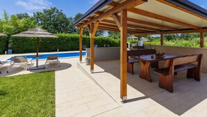 A covered outdoor area with a pool, wooden furniture, and umbrellas. - Villa Paliska by Interhome (Poreč)