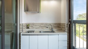 Una cocina moderna con un lavamanos de acero inoxidable, una estufa empotrada y un salpicadero de baldosas rectangulares.