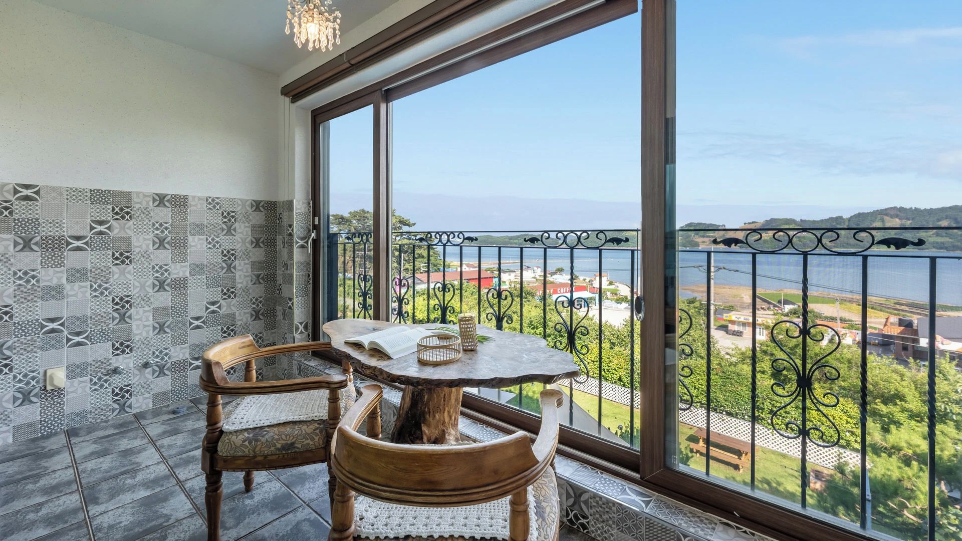 Un balcón con vistas a una masa de agua, una mesa con sillas y azulejos con diseño.