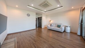 Un salón amplio con un sofá blanco, una lámpara de pie y un diseño de techo moderno.