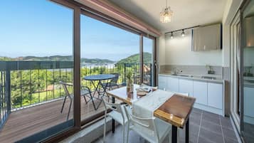 Un balcón con mesa y sillas, una zona de cocina con pileta y armarios, y vista al paisaje.