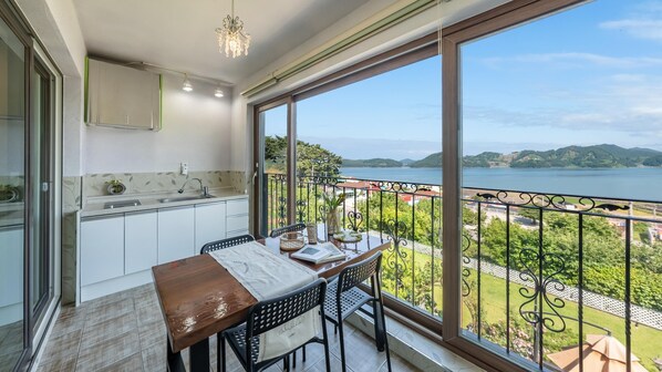 Un balcón con mesa y sillas, vista a un lago, y una zona de cocina con pileta y armarios.