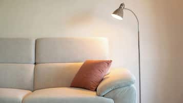 A sofa with a single cushion against a wall, and a floor lamp to the right.
