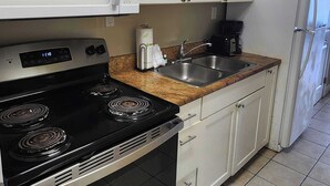 A kitchen with white cabinets, a black stove, a microwave, a sink, and a refrigerator. - Caravelle 841 (Myrtle Beach)