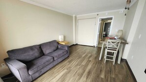 A living room with a grey sofa, a wooden dining table with chairs, and a white door in the background. - Caravelle 841 (Myrtle Beach)