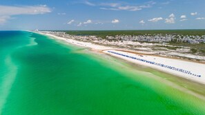 An aerial view of a coastal area with a beach, a row of beachside buildings, and a clear sky. - "Vitamin Sea" | Beachfront | 4 Bikes Included (Inlet Beach)
